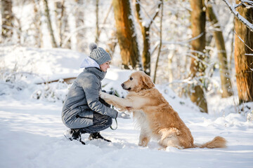 Teenage Girl With Golden Retriever Gives Paw In Snowy Forest, Sitting With Dog