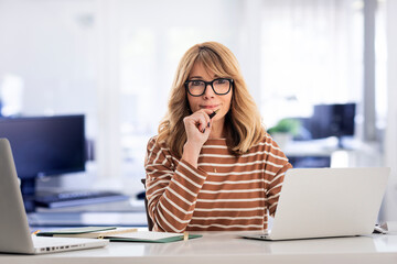 Blond haired businesswoman sitting at the office and using laptops for work