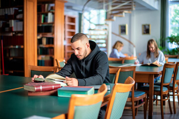 Handsome young man sitting in the university library and learning