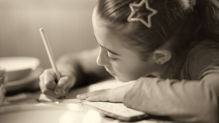 A young girl making school homework in the kitchen