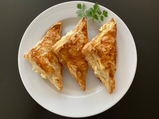 Gefüllte Blätterteigtaschen auf einem weissen Teller angerichtet mit Petersilie garniert ......