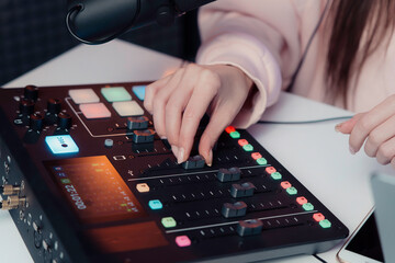 Close-up of a podcaster's hands as she expertly adjusts an audio mixer, fine-tuning the sound for a live podcast recording - obrazy, fototapety, plakaty