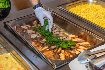a bowl filled with salmon steaks at a buffet - hand with gloves