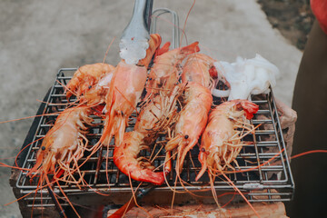 two hands holding frosty mugs of beer, one full and one half-empty, during what appears to be a social event.
