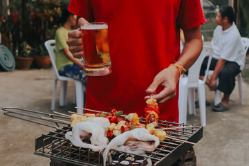 two hands holding frosty mugs of beer, one full and one half-empty, during what appears to be a social event.