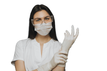 Professional nurse wearing protective glasses, a surgical mask and a medical gown wears her gloves  against transparent background, preparing to exam a new patient. Covid-19 virus concept.
