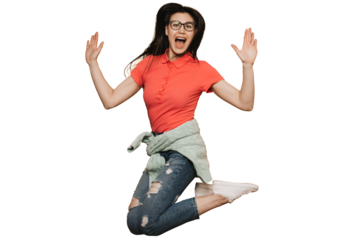 Young brunette girl in glasses, wearing red t-shirt, jeans, sweater tied at waist and white sneakers, jumping high, screaming against transparent background, raising up her hands, enjoying a holiday