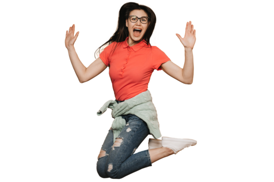 Young brunette girl in glasses, wearing red t-shirt, jeans, sweater tied at waist and white sneakers, jumping high, screaming against transparent background, raising up her hands, enjoying a holiday