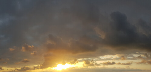 Naklejka na ściany i meble Dark storm cloud with golden sun on dramatic sunset sky