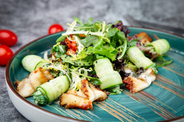 salad with arugula, lettuce, cucumber rolls, fish and sesame seeds, top view