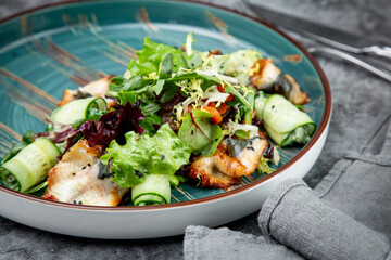salad with arugula, lettuce, cucumber rolls, fish and sesame seeds, top view