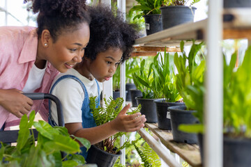 African mother and daughter is choosing tropical fern and ornamental plant from the local garden center nursery during summer for weekend gardening and outdoor - obrazy, fototapety, plakaty