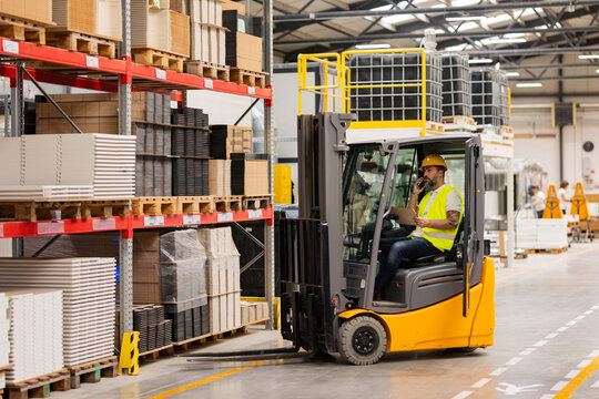 Warehouse worker driving forklift. Warehouse worker preparing products for shipmennt, delivery, checking stock in warehouse, order picking.