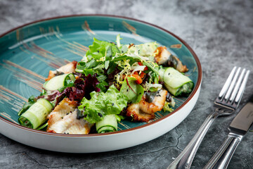 salad with arugula, lettuce, cucumber rolls, fish and sesame seeds, top view