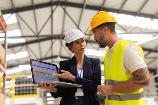 Female manager talking with foreman, checking production plan on notebook. Woman quality controller checking quality of products, talking with technician. - Powered by Adobe