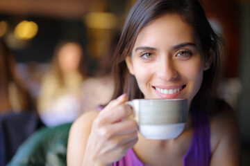 Happy restaurant customer looking at you with a coffee