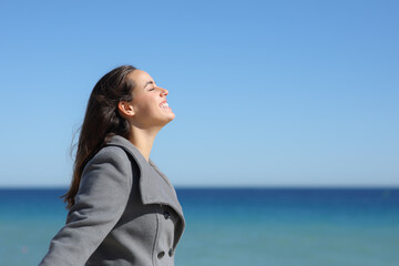 Happy woman breathing fresh air in winter on the beach