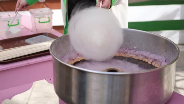 Female hands preparing cotton candy from sugar