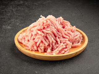 Plate of raw minced chicken fillet on grey background