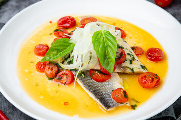 unpeeled fish with gravy, herbs, cherry tomatoes and onions, top view