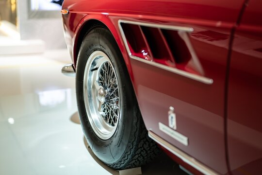Detail of Ferrari 275 GTS red sports car in Museum Enzo Ferrari Modena focused on the wire wheel knock-off spinner