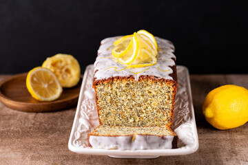 Sliced pound cake made with lemon zest, sugar and lemon glaze and poppy seeds on a brown table and...