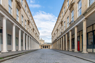 View through Bath Street, Bath, Somerset, UK with buildings with typical Georgian architecture and columns and entrance to ancient Roman Baths at end of street