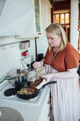 Woman cook at home in kitchen frying vegetables on stove
