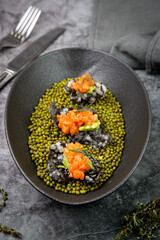 black caviar, red fish and wassabi on a plate with peas, top view