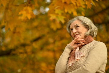 Senior woman walking in the park in autumn. 