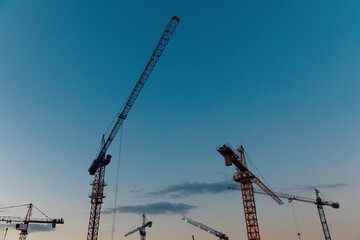 Construction cranes in the evening at the construction site of buildings