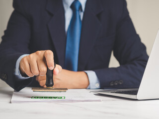 Businessman stamped for passed documents while sitting in the office.