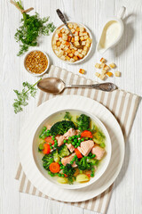 salmon, veggies and green herbs soup in bowl