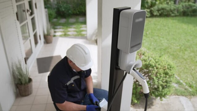 Qualified technician install home EV charging station, providing maintenance service for electric vehicle's battery charging platform at home. EV car technology for residential utilization. Fastidious