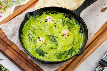 broccoli cream soup with herbs, cheese and tortillas in a frying pan, top view