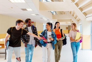Obraz premium multiracial group of boys and girls classmates walking happily together through the halls of their school, campus or high school.