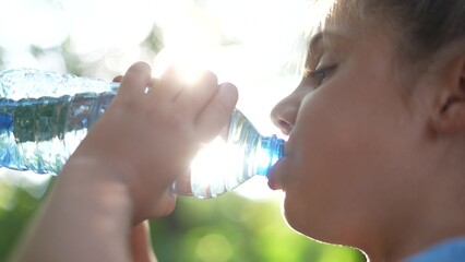 child drinking water from a plastic bottle. water shortage problem on earth concept. water shortage...