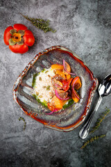 side view of a dish of baked persimmons, colored peppers, rice and seeds