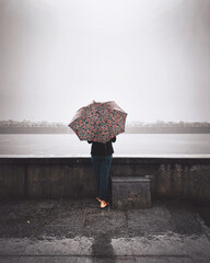 girl standing at riverside holding colorful umbrella 