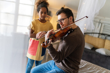 Single father and adopted daughter playing on instrument together.Adult man playing violin for child