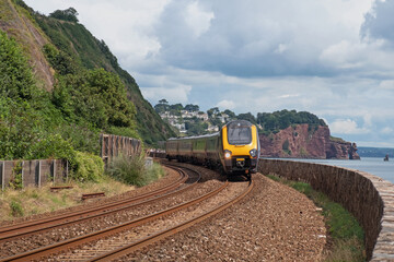 A passenger train en route to nearby Teignmouth and beyond, here passing close to the walkway on the atmospheric line following the coastline through Devon UK