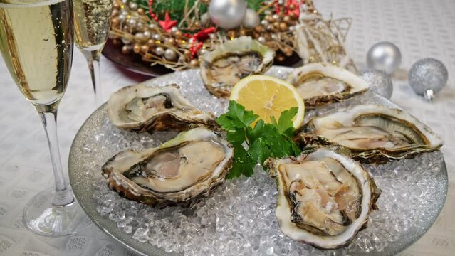 Fresh oysters on ice rotating, Christmas New Year decoration, glasses of champagne. Close up