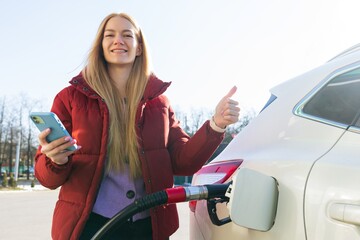 Young woman pays for a gas station using an app on her phone.The woman gives a thumbs up.