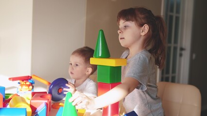 kids girl and baby play in kindergarten. a group of children play toys cubes and cars on the table in kindergarten. happy family preschool education concept. nursery indoor baby toddler home