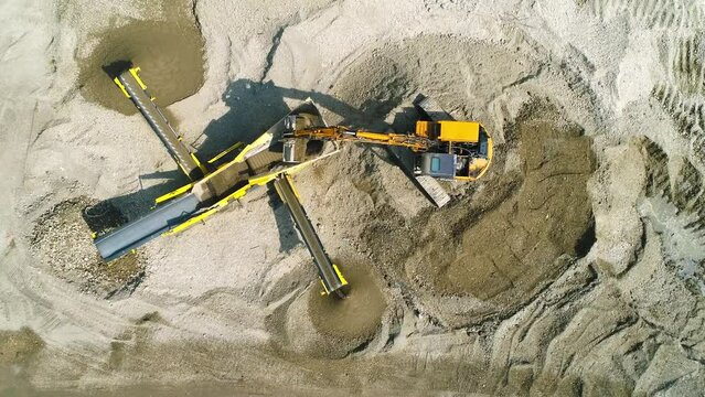 The excavator loads screening machine in construction site. High angle static clip.