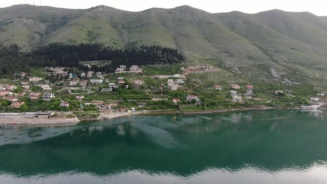 Drone view in Albania flying over Shkod&euml;r lake in Pogradec on cloudy day with green mountains on the back horizontal move