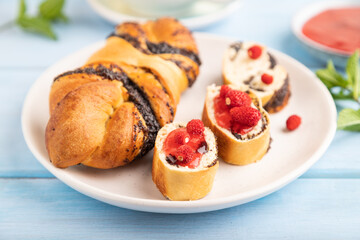 Sweet bun with strawberry jam on a blue wooden background, side view, selective focus.