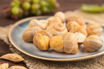 Grape (Burgundy) snails with butter and cheese on brown wooden, side view, selective focus