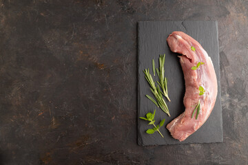 Raw pork meat with herbs and spices on slate cutting board on black concrete. Top view, copy space.