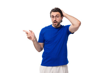 Fototapeta premium young brunette european man with a beard in a blue t-shirt looks away on a white background with copy space
